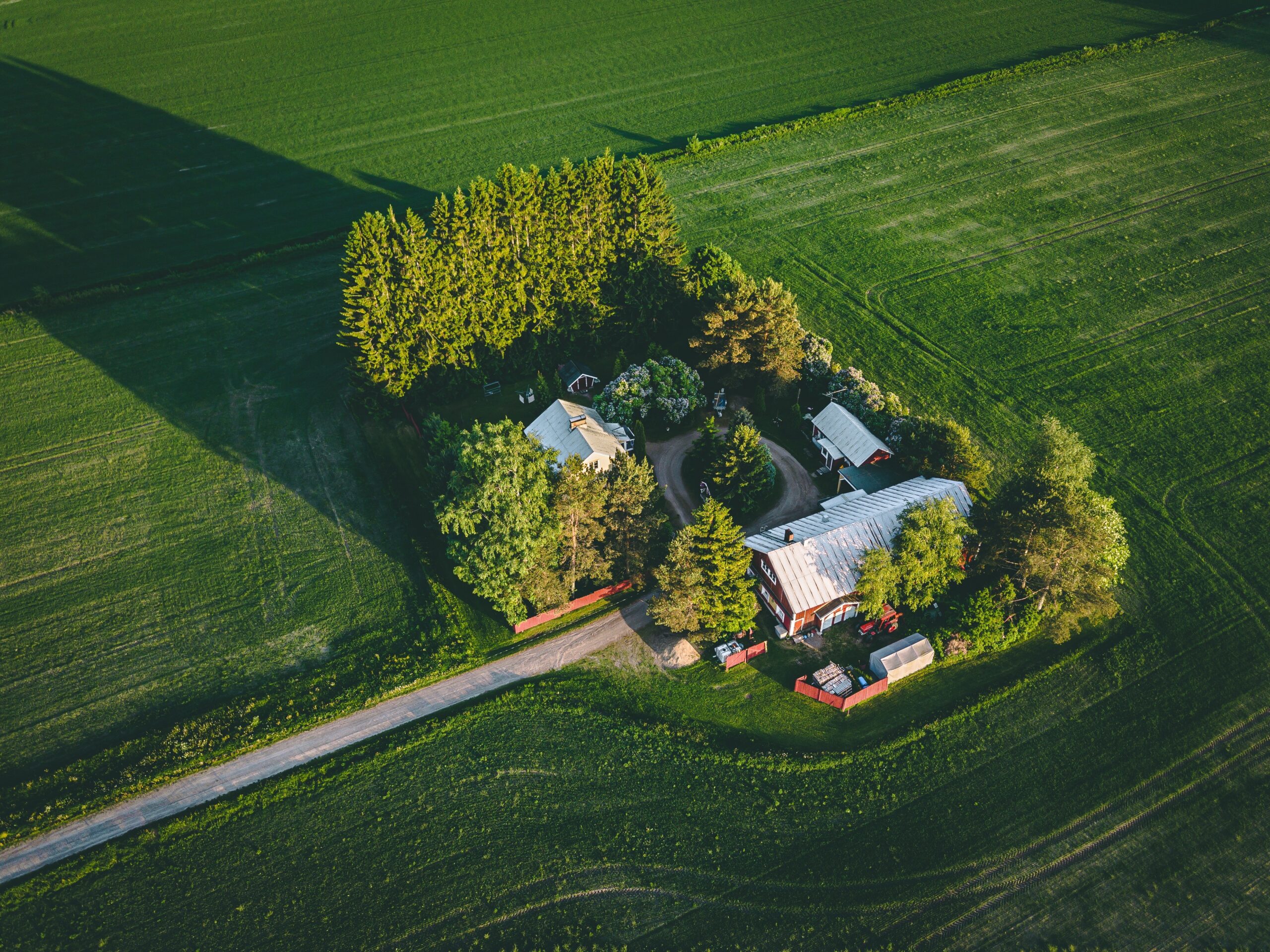 Aerial view of farmland with red barn and houses and harvest field in Finland